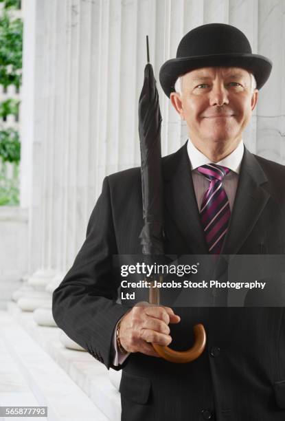 caucasian businessman with derby carrying umbrella - シルクハット ストックフォトと画像