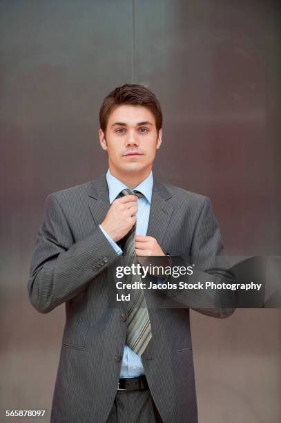 caucasian businessman adjusting tie - tied up stockfoto's en -beelden