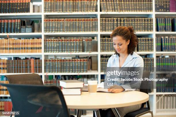 mixed race businesswoman reading at desk in law library - law library stock pictures, royalty-free photos & images