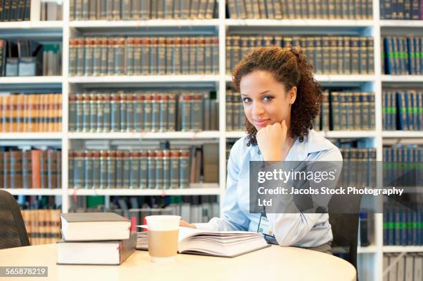 mixed race businesswoman reading at desk in law library - law book stock pictures, royalty-free photos & images