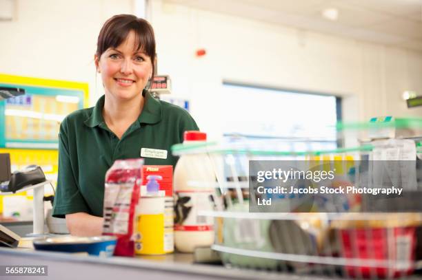 caucasian cashier working at grocery store checkout - female supermarket stock-fotos und bilder