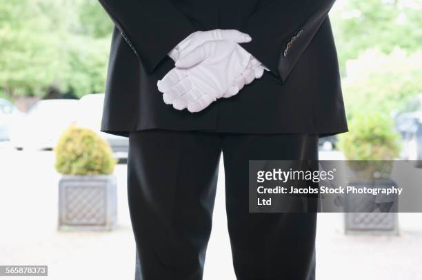 close up of caucasian butler waiting at hotel entrance - valet stockfoto's en -beelden