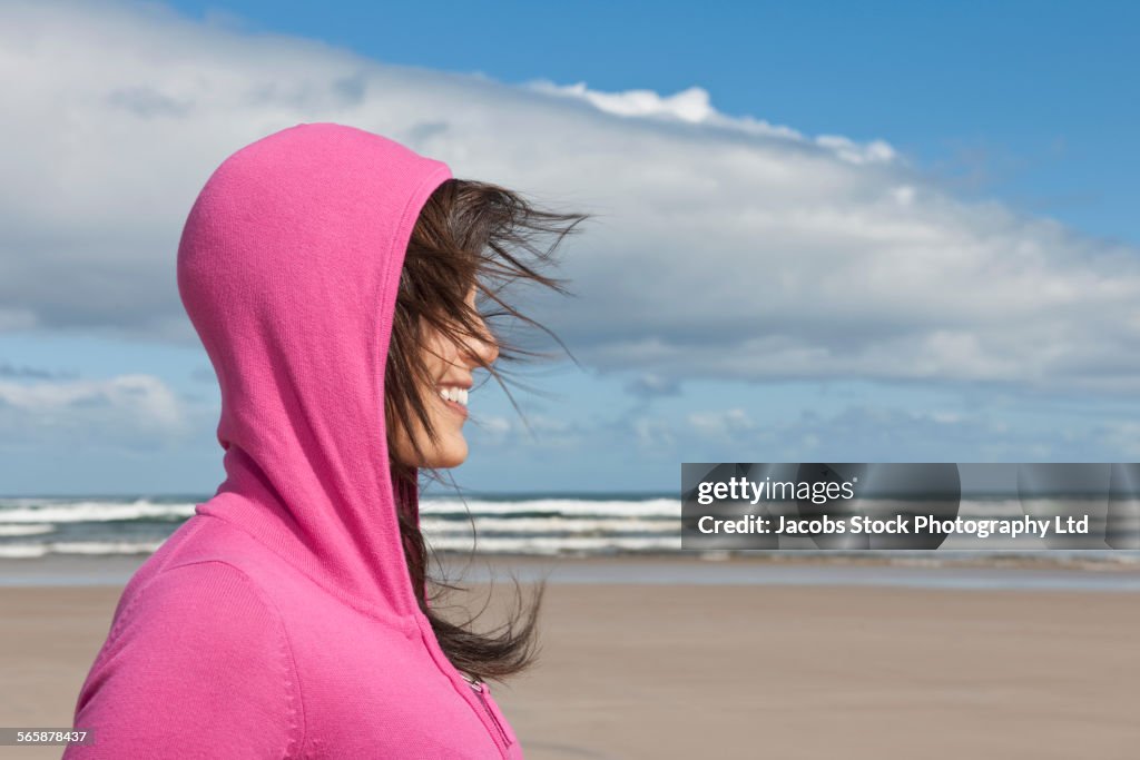 Hispanic woman wearing hoody on windy beach