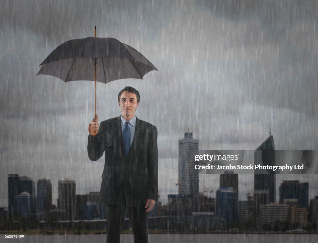 Hispanic businessman standing under umbrella in rain, Perth, Western Australia, Australia