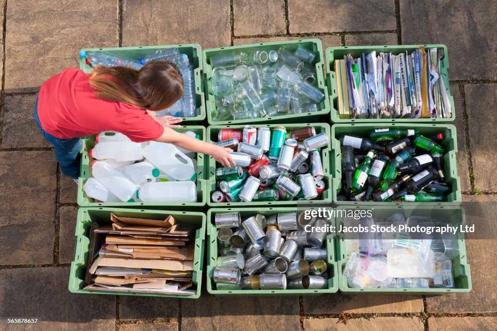 Caucasian teenage girl organizing recycling bins