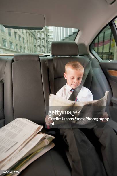 caucasian boy playing businessman in back seat of car - child prodigy foto e immagini stock