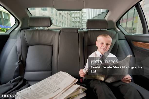 caucasian boy playing businessman in back seat of car - child prodigy foto e immagini stock