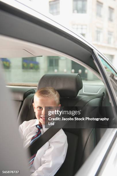 caucasian boy playing businessman in back seat of car - child prodigy foto e immagini stock