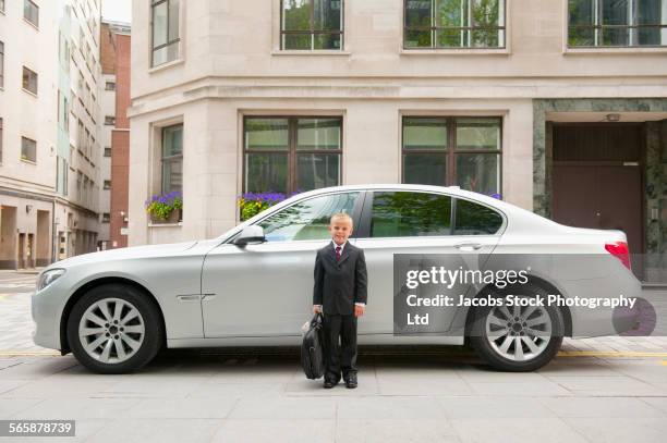 caucasian boy playing businessman near car - child prodigy stock-fotos und bilder