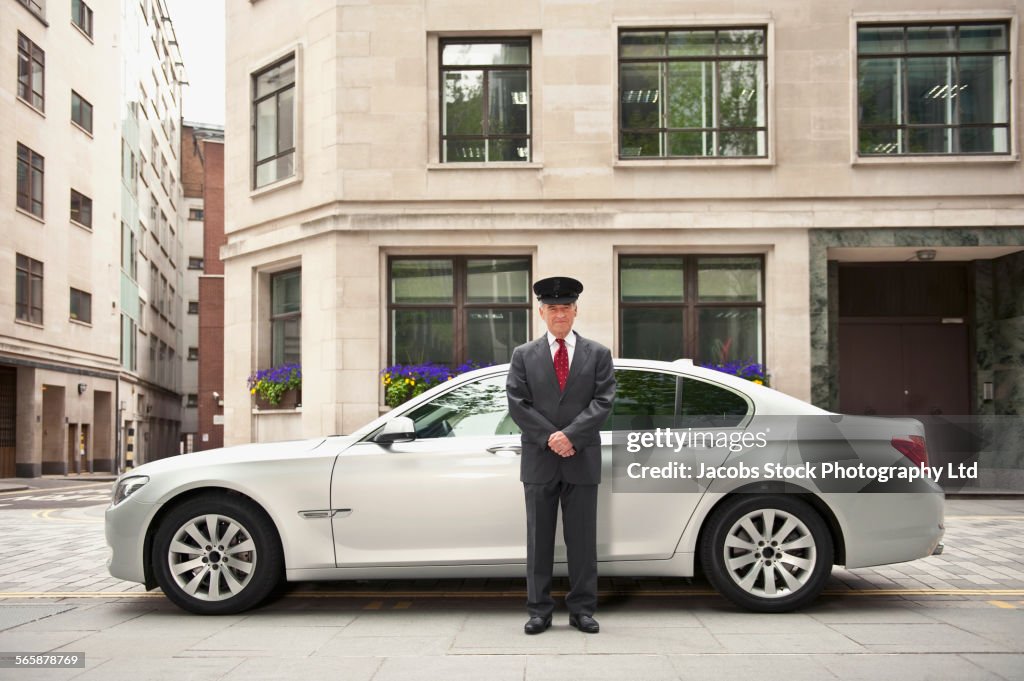 Caucasian driver standing near car in city