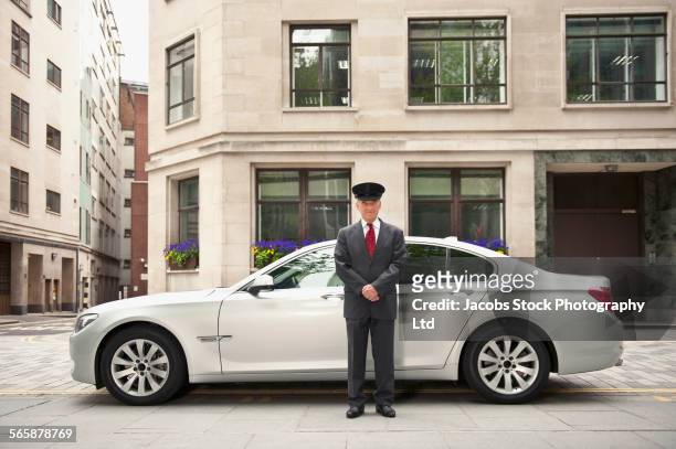 caucasian driver standing near car in city - chauffeur 個照片及圖片檔