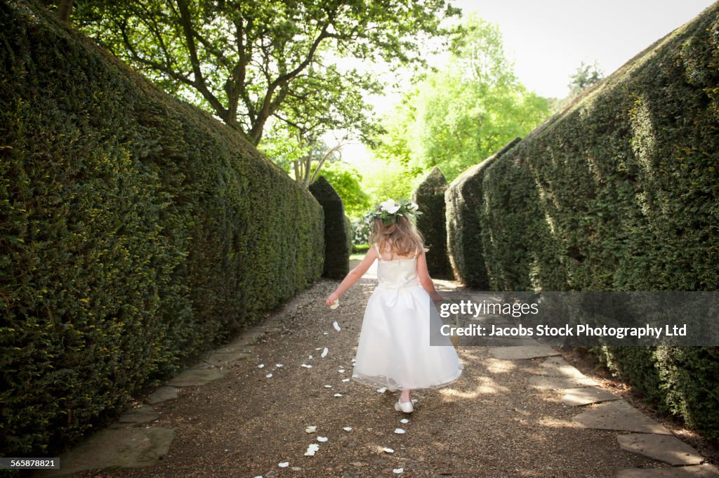 Caucasian flower girl sprinkling petals in garden