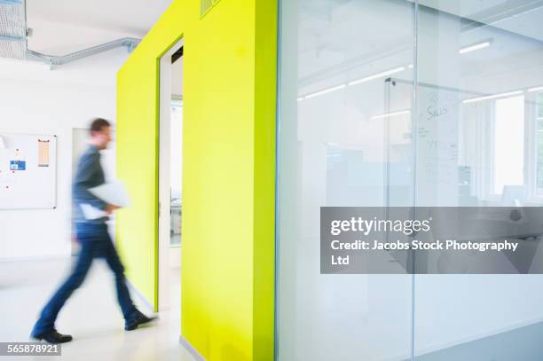 blurred view of caucasian businessman walking in office - blurry office stock-fotos und bilder