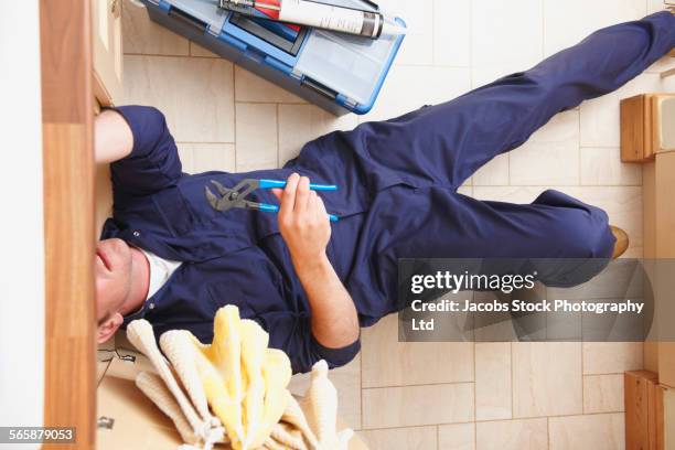 overhead view of caucasian plumber repairing sink - plumber stock pictures, royalty-free photos & images
