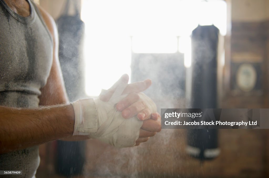 Caucasian boxer chalking hands in gymnasium