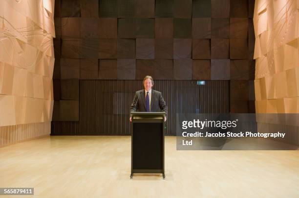 caucasian businessman standing at podium on stage - rednerpult stock-fotos und bilder