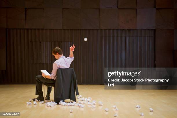 caucasian businessman tossing crumpled paperwork in barren room - throwing fotografías e imágenes de stock