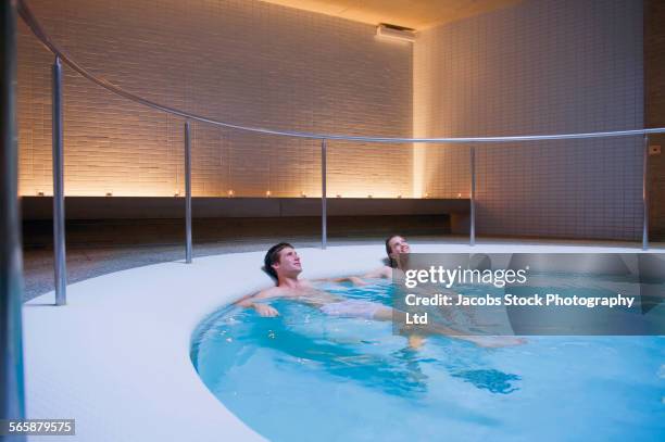 couple relaxing in soaking pool in spa - trattamento di benessere foto e immagini stock