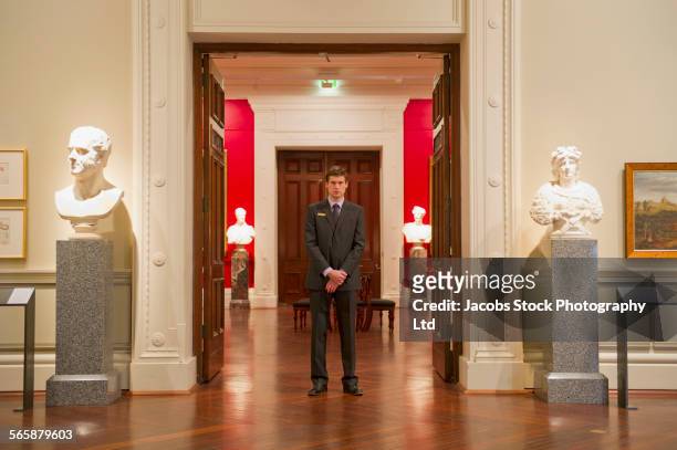 caucasian security guard standing in art museum - museum entrance stock pictures, royalty-free photos & images