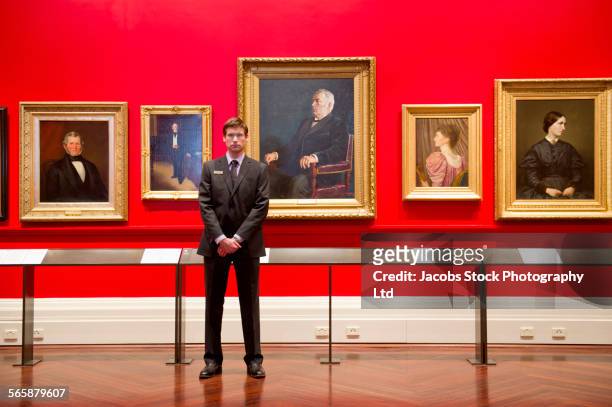 caucasian security guard standing in art museum - guard stockfoto's en -beelden