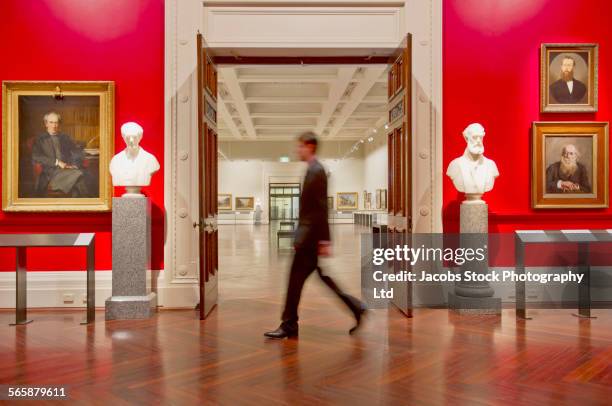blurred view of caucasian security guard walking in art museum - museum foto e immagini stock