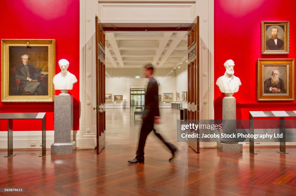 Blurred view of Caucasian security guard walking in art museum
