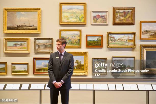caucasian security guard standing in art museum - garder photos et images de collection