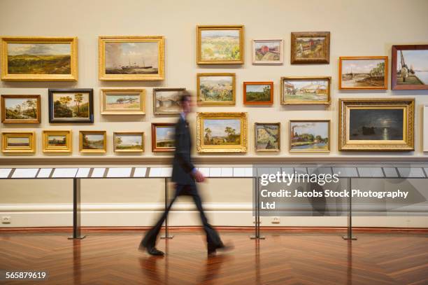 blurred view of caucasian security guard walking in art museum - arte imagens e fotografias de stock