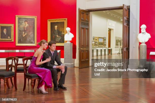 caucasian couple in evening wear sitting in art museum - bust museum stock-fotos und bilder