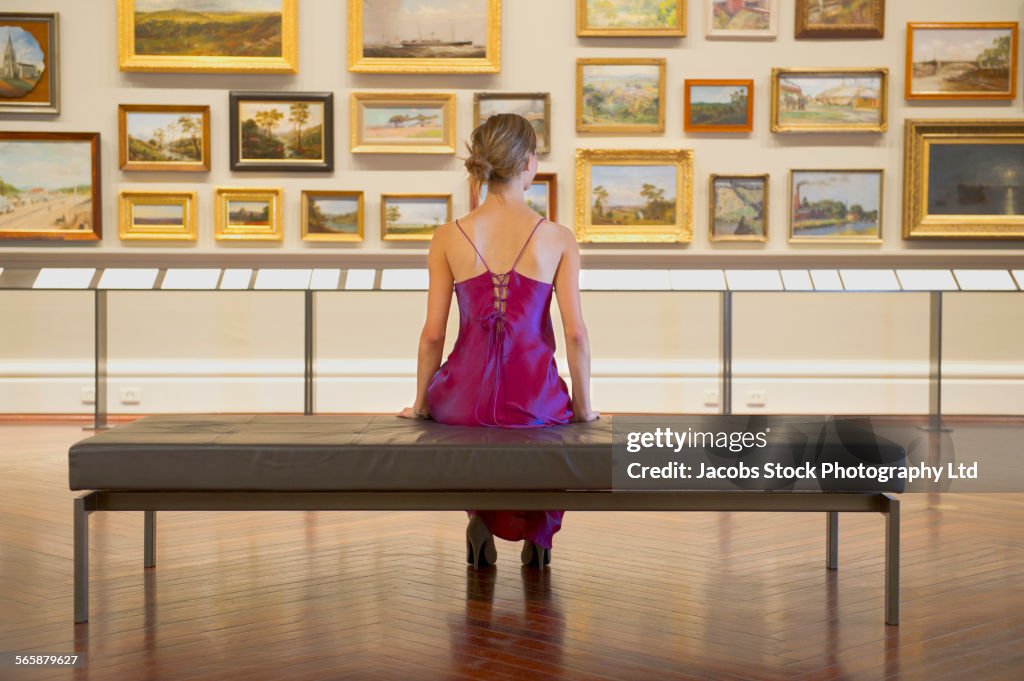 Caucasian woman in evening gown admiring art in museum