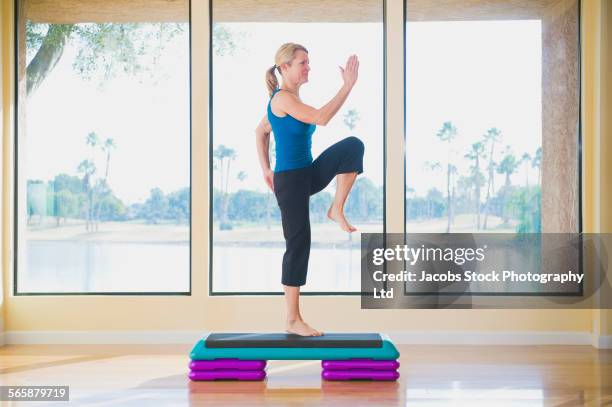 caucasian woman doing aerobic exercises near window - aerobics stock pictures, royalty-free photos & images