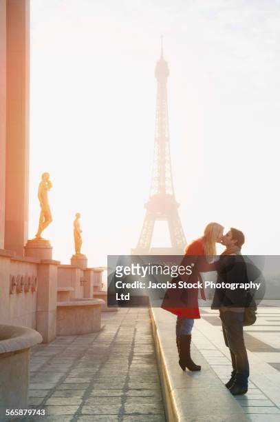 caucasian couple kissing near eiffel tower, paris, ile-de-france, france - weekender stock pictures, royalty-free photos & images
