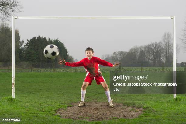 dirty caucasian boy guarding goal in soccer field - child goalie stock pictures, royalty-free photos & images