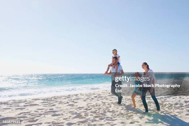 caucasian parents and children walking on beach - family with two children stock pictures, royalty-free photos & images