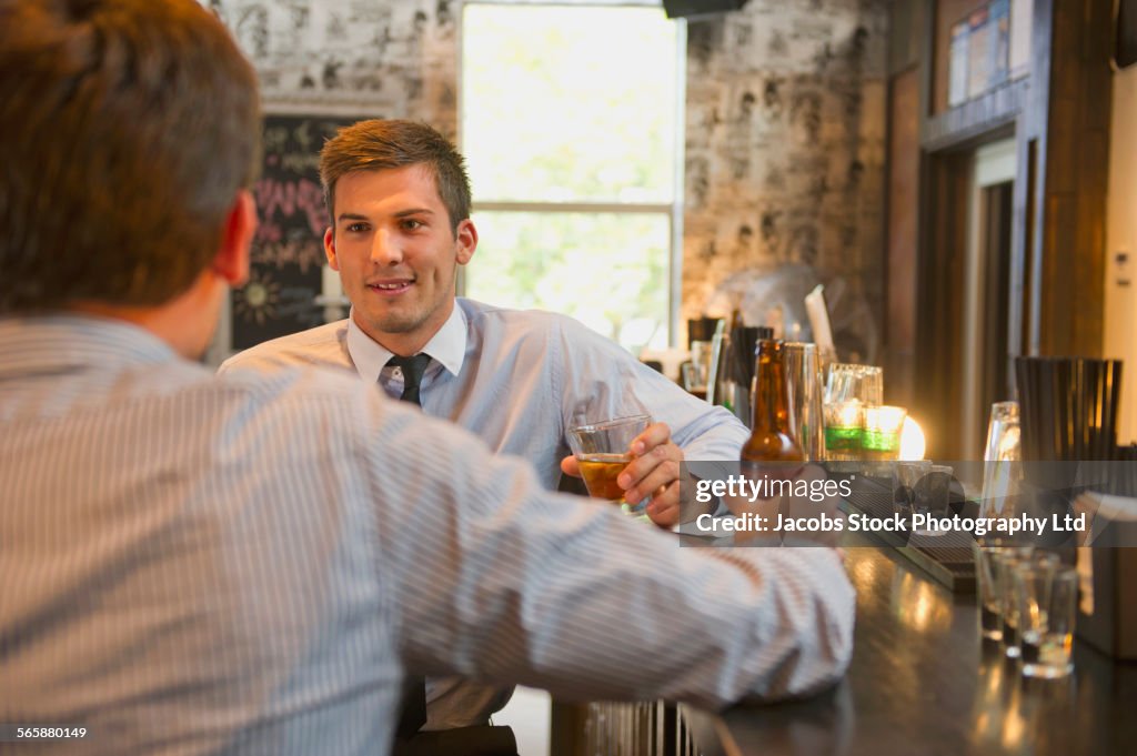 Businessmen talking and drinking at bar