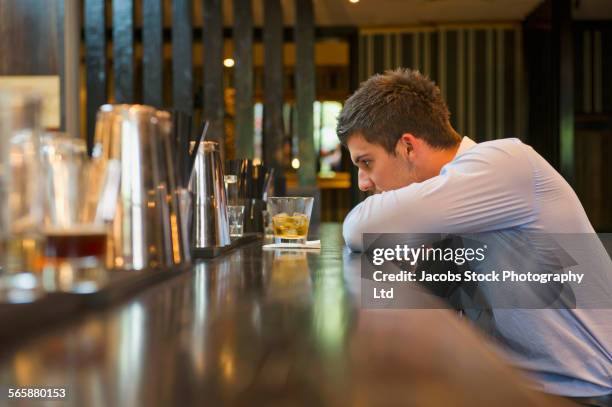 lonely hispanic businessman sitting at bar - alkoholmissbrauch stock-fotos und bilder