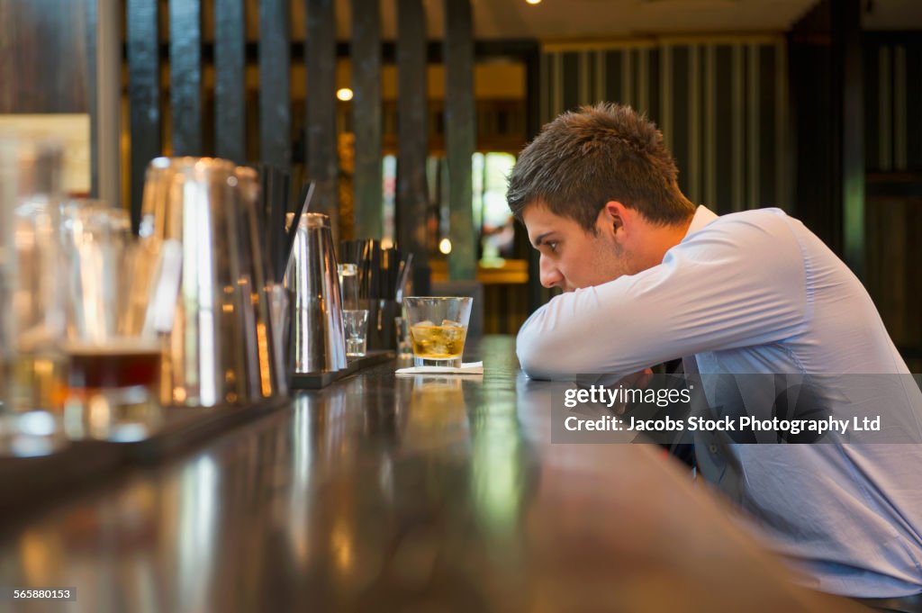 Lonely Hispanic businessman sitting at bar