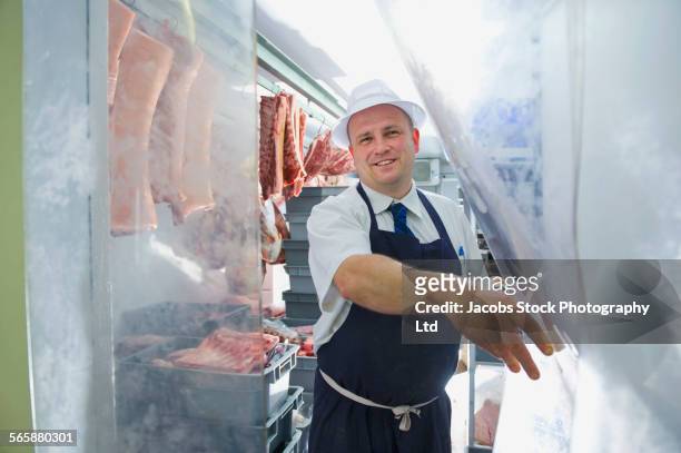 caucasian butcher standing in freezer in shop - butcher portrait imagens e fotografias de stock