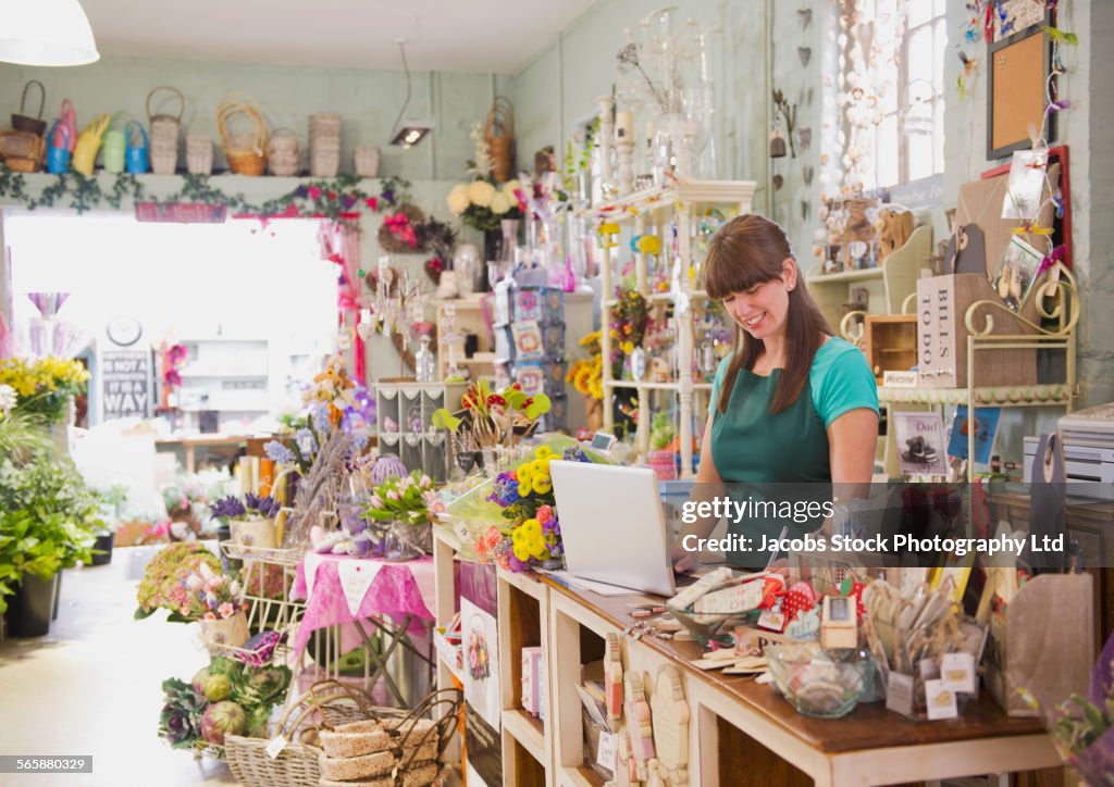 Caucasian employee working on laptop in gift shop