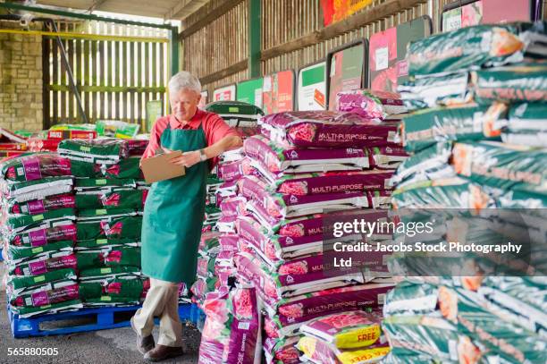 caucasian gardener checking inventory in nursery - adubo equipamento agrícola imagens e fotografias de stock