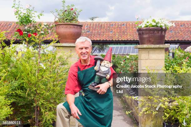 caucasian gardener holding garden gnome in nursery - garden gnome stock pictures, royalty-free photos & images