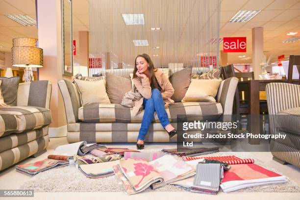 caucasian woman examining fabric swatches in furniture store - furniture store stock-fotos und bilder