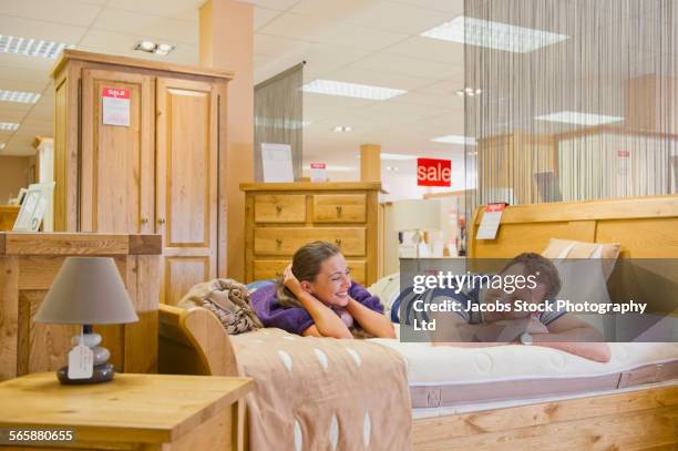 caucasian couple testing mattress in furniture store - mattress stock pictures, royalty-free photos & images