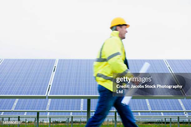 blurred view of caucasian technician walking near solar panels - technical drawing stock pictures, royalty-free photos & images