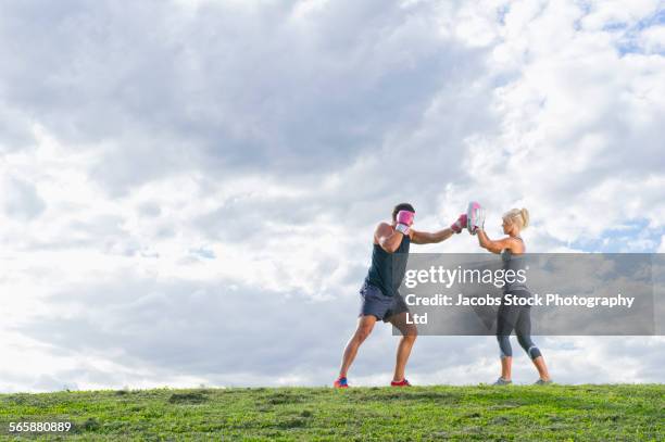 caucasian couple boxing in grass field - sparring stock-fotos und bilder