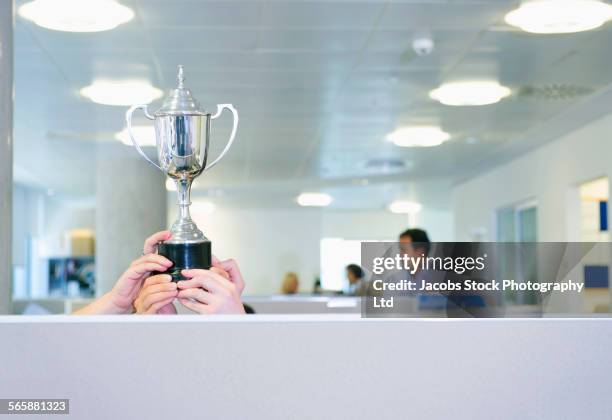 businesswoman holding trophy over office cubicle - cup office stock pictures, royalty-free photos & images