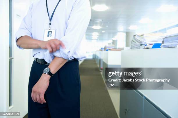 mixed race businessman rolling sleeves in office - lanyard stock pictures, royalty-free photos & images