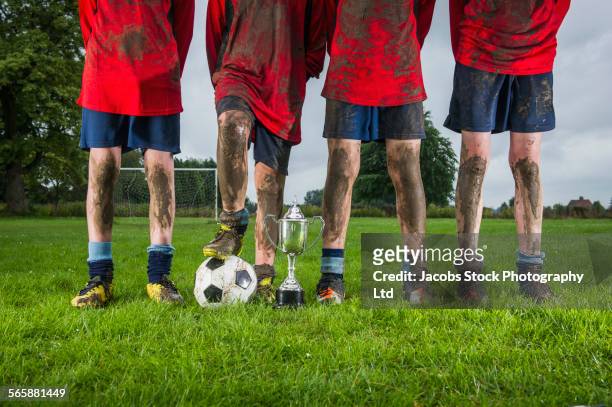 dirty caucasian soccer team with trophy and ball in field - muddy football pitch stock pictures, royalty-free photos & images