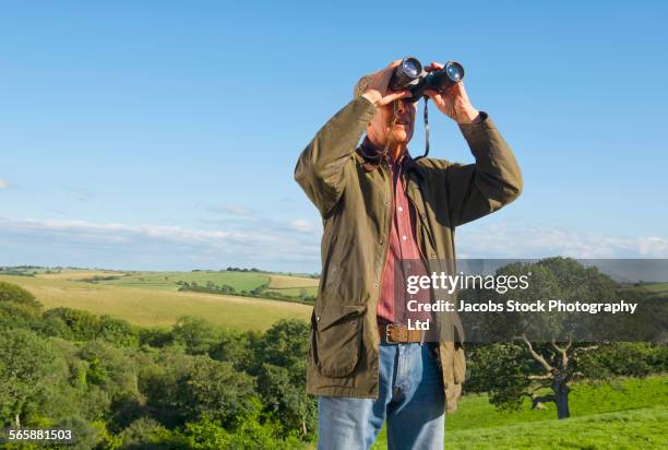 caucasian man bird watching with binoculars in rural field - fågelskådning bildbanksfoton och bilder