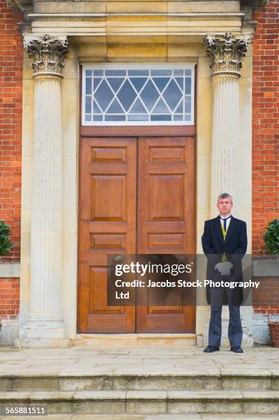 caucasian butler standing outside mansion front door - valet stockfoto's en -beelden